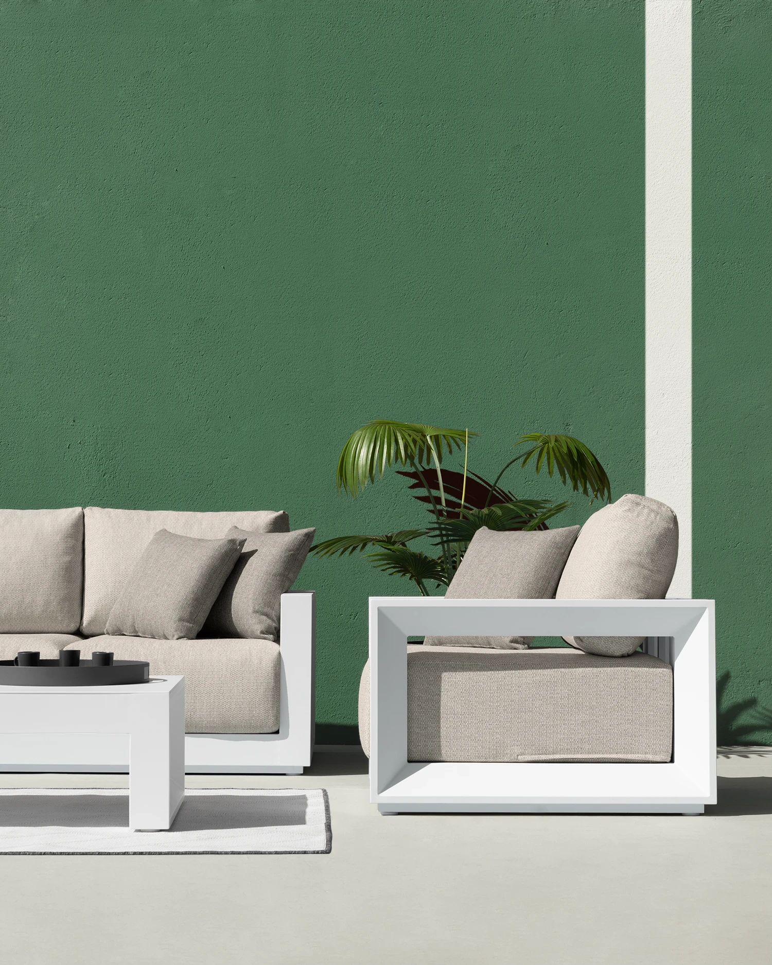 White side table and sofas with pearl grey textiles, arranged in an outdoor space with a green wall