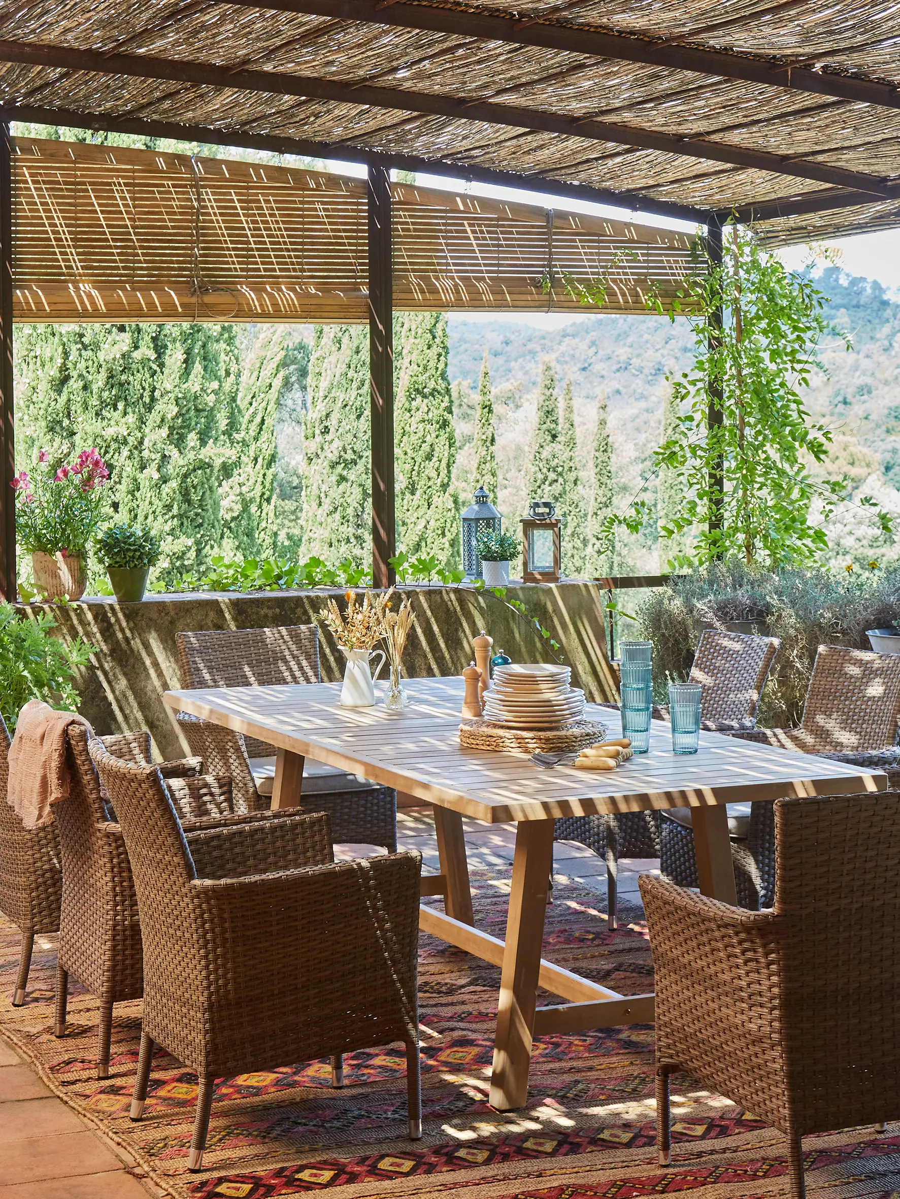 Conjunto de comedor exterior en ratán sintético, y mesa de madera.